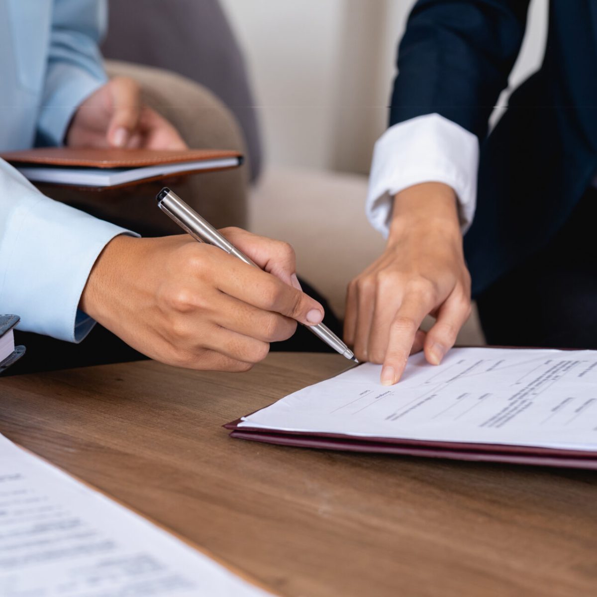 Couple clients signing paper contract with professional broker or realtor, after discussing agreement details.